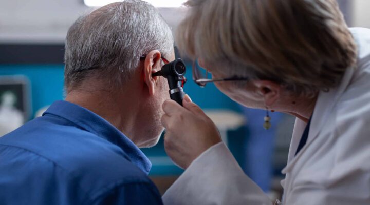 Profesional sanitario realizando revisión auditiva para extracción de tapón de cerumen en casa en Granada